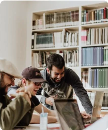 A group of people in the library in front of a laptop